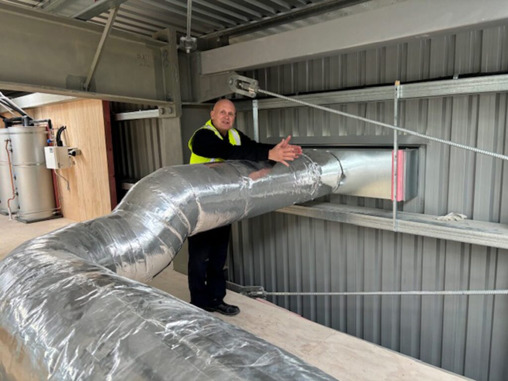 Man standing next to ducted ventilation system installed by Beattie Air in a commercial warehouse in Christchurch, Canterbury